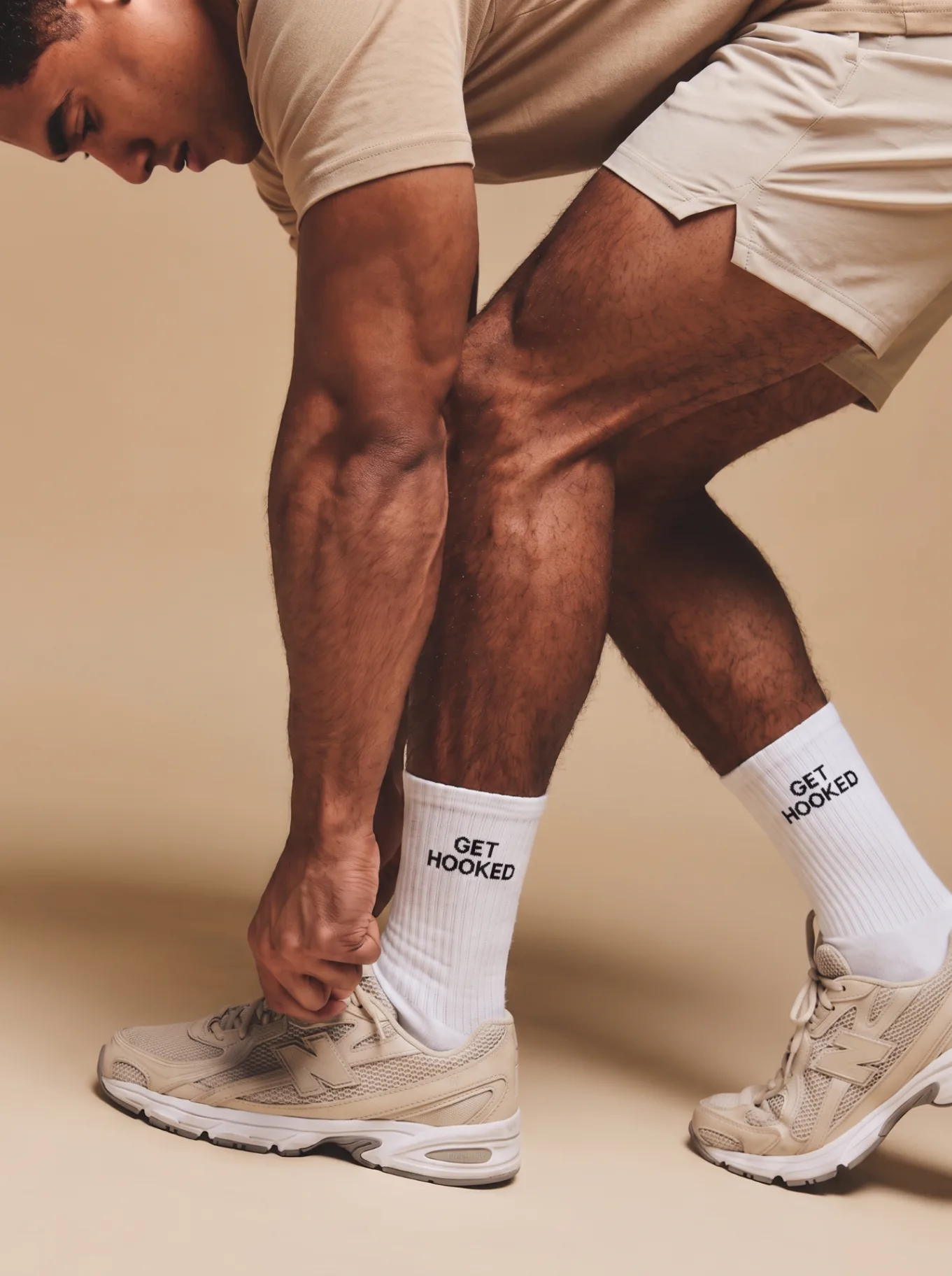 Model wearing white custom branded crew socks with 'GET HOOKED' embroidered text, styled with athletic sneakers