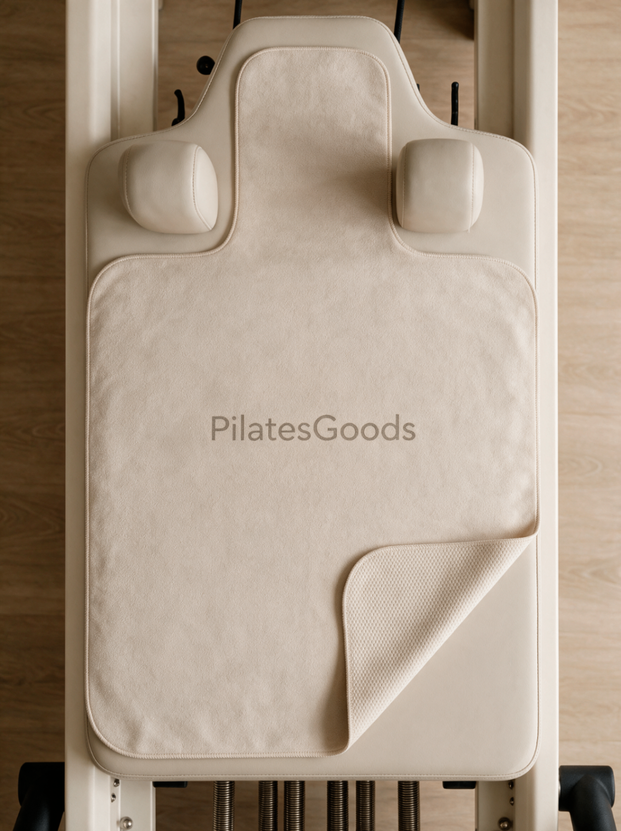 Custom branded reformer grip towels in navy, pink, beige and teal with Pilates Goods logo on Pilates reformer equipment