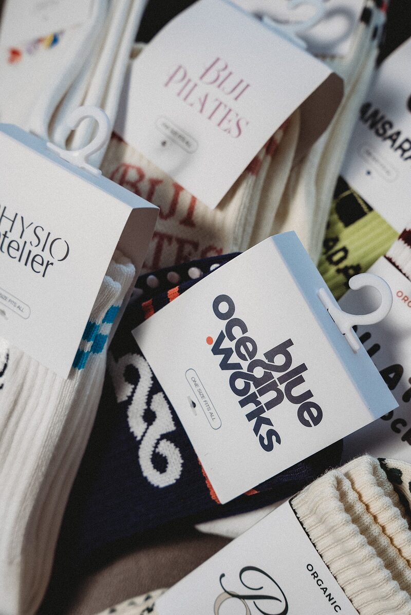 Pilates studio member carrying custom branded tote bag with studio logo and grip sock packaging