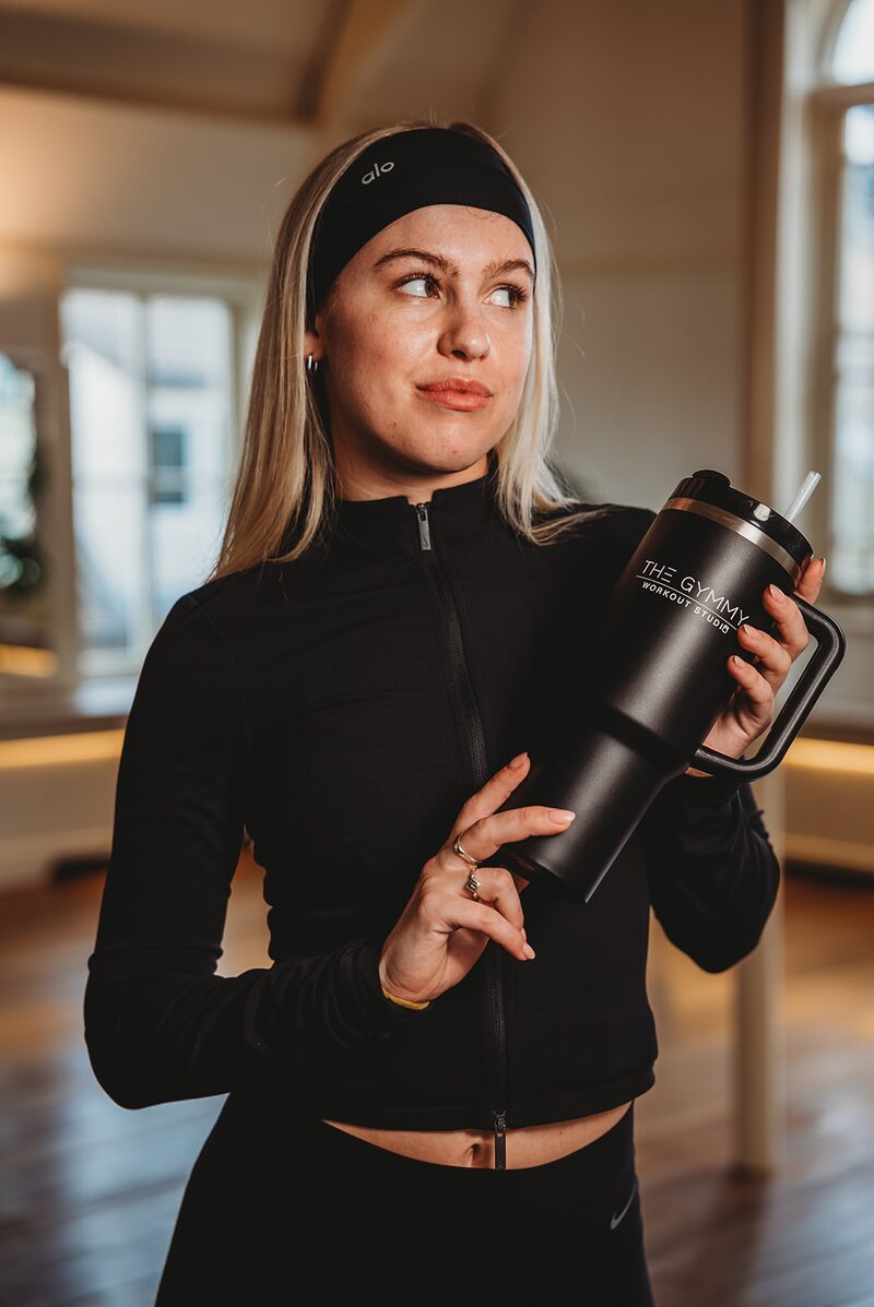 Pilates studio member holding custom branded mega cup with studio logo after class