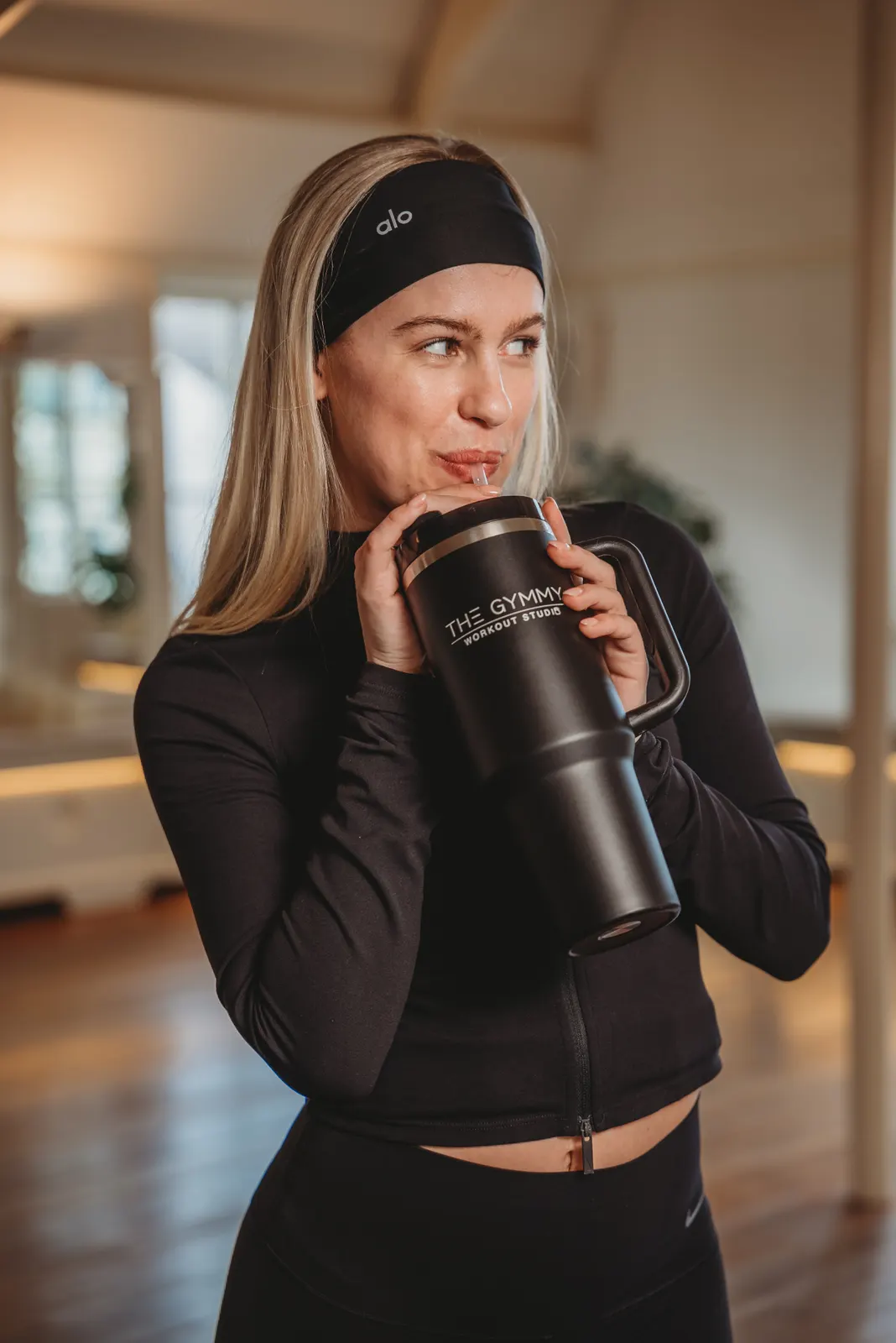 Pilates studio member holding custom branded The Gymmy mega cup with engraved logo